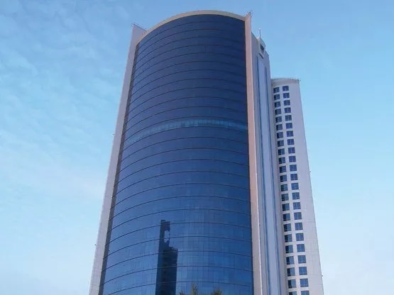 The iconic Bahrain Financial Harbour, a striking example of modern architecture with its twin towers soaring into a blue, cloud-dotted sky—home to prestigious Servcorp serviced offices,